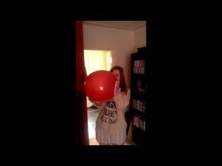 scared girl blows to pop red balloon at home